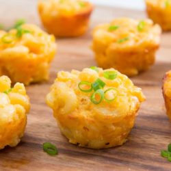 Mac and Cheese Cups Served on Wooden Board with Scallions On Top